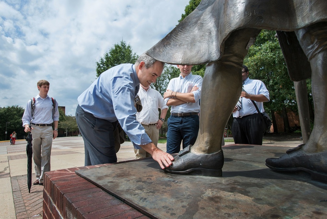 President Ángel Cabrera rubs the toe of the George Mason statue for good luck.